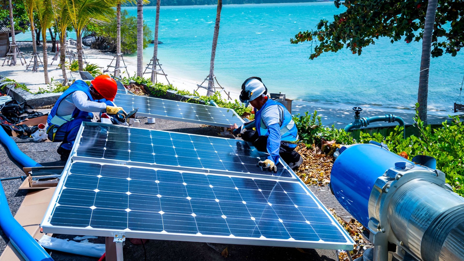 Deux techniciens travaillent sur une installation solaire destinée à alimenter un module de traitement d'eau Renewable Water NC, sur une île calédonienne.